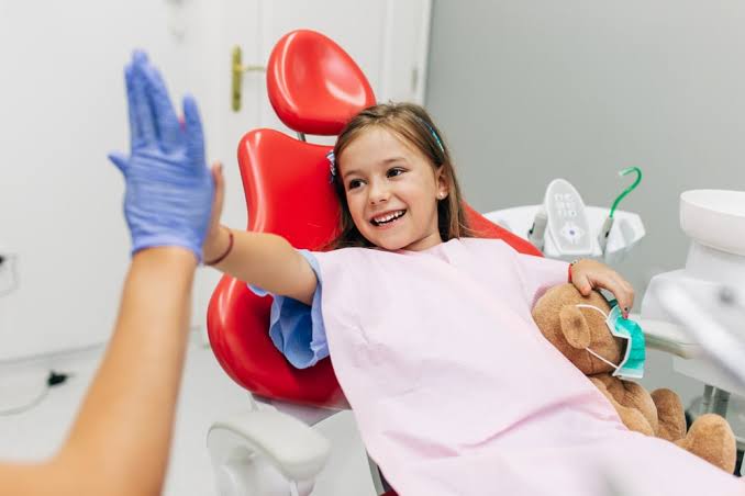 Enfant souriant installé dans le fauteuil du cabinet pédiatrique